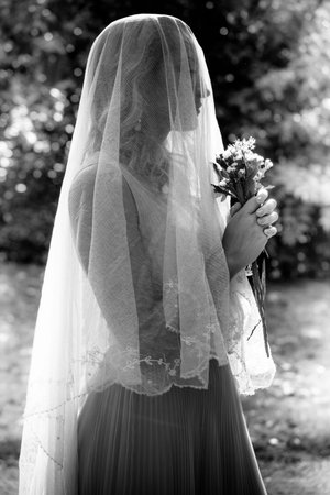 portrait of bride with veil and bouquet of wild flowers outdoor shot  summer day outdoor bw