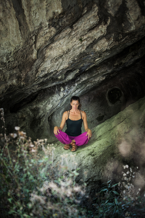 woman practice yoga in small cave on trip to mountain summer dayの写真素材