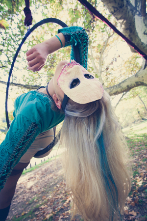 young woman aerial hoop  dance in forest with mask on faceの写真素材