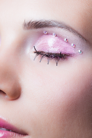 closeup of woman face with pink makeup eyelashes and crystals studio shotの写真素材