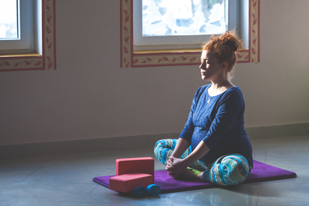 red head pregnant young woman on yoga class indoor full body shotの写真素材
