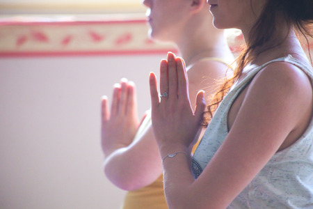 couple of women on yoga class closeup of hands in namaste gesture indoor natural lightの写真素材