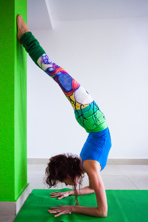 woman practice handstand against wall yoga class indoor side viewの写真素材