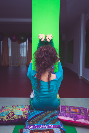 young woman practice yoga stretching against column indoor back viewの写真素材