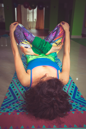 young woman lying on mat with legs in lotus position indoor shot from above viewの写真素材