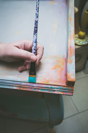 woman hand with brush paint wooden desk with chalky paint closeupの写真素材