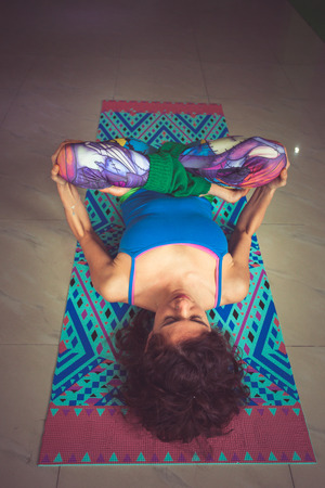 young woman lying on mat with legs in lotus position indoor shot from above viewの写真素材