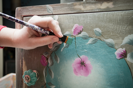 woman hand with a brush  paint with chalky paint wooden dresser diy closeup hobby ideas の写真素材