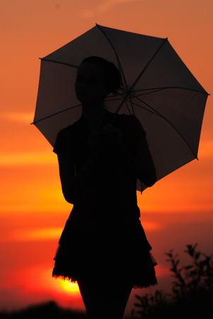 The girl with the umbrella and the sunset, silhouetteの写真素材