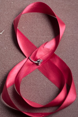 pink ribbon with a ring on a wood background, greetings on happy women's dayの写真素材