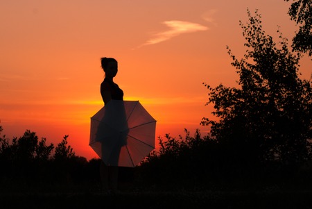 The girl with the umbrella and the sunset, silhouetteの写真素材