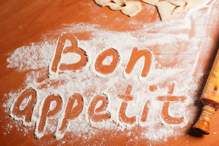 The inscription bon appetit on the table with flour , dough and donutsの写真素材