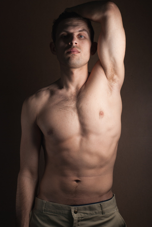 A portrait of a hot guy man without a shirt against dark backgroundの写真素材