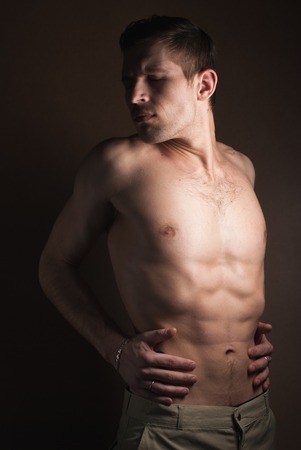 A portrait of a hot guy man without a shirt against dark backgroundの写真素材