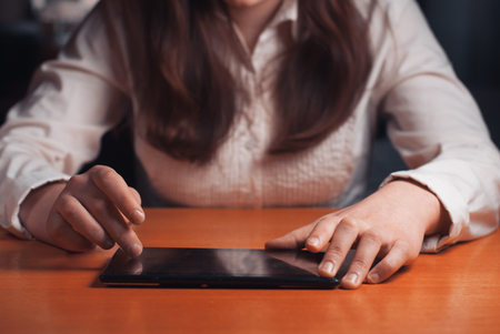 young girl works on the tablet at the table, surfing the Internetの写真素材