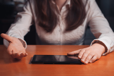 young girl works on the tablet at the table, surfing the Internetの写真素材