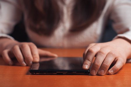 young girl works on the tablet at the table, surfing the Internetの写真素材