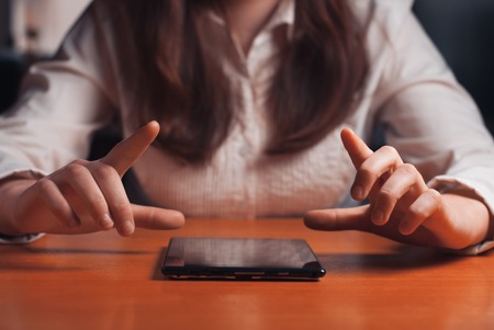 young girl works on the tablet at the table, surfing the Internetの写真素材