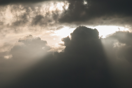 sun breaking through a cluster of Cumulus cloudsの写真素材