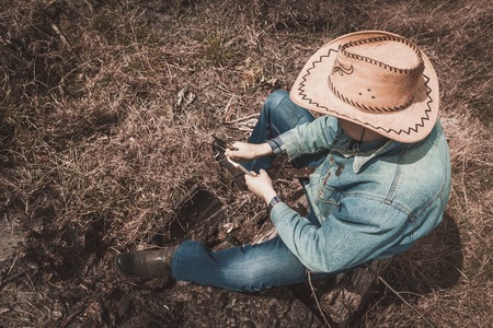 Cowboy sits on the dry grass, a Man in a cowboy hatの写真素材