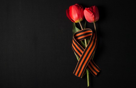 May 9: St. George ribbon and red tulips on a black backgroundの写真素材