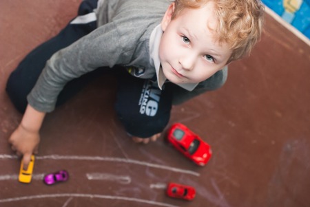 Little boy playing with toy cars, a boy with blond hair posingの写真素材