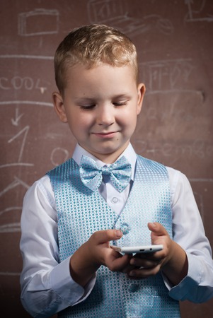 boy in suit on the background of the school Board, the young blonde with the phoneの写真素材