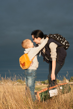 Mom and son go for a walk outside the city, the girl and her baby are on the road against the skyの写真素材