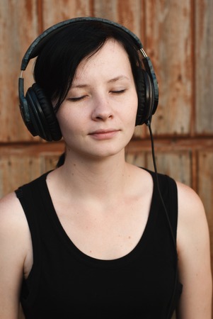 woman with headphones listening to music, brunette in a black shirt dancing to her favourite songの写真素材
