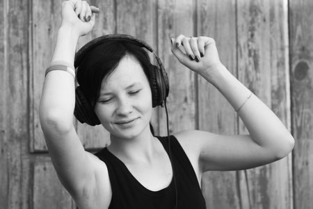 woman with headphones listening to music, brunette in a black shirt dancing to her favourite songの写真素材