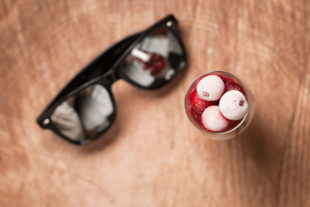 frozen cherries in the glasses and sunglasses on a wooden table , fresh berriesの写真素材
