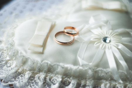 Golden wedding rings on white pillow aの写真素材