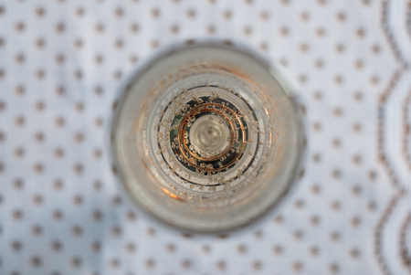 Gold engagement ring in a glass of champagne. Creative photography with champagne bubbles, glittering in the sunlightの写真素材