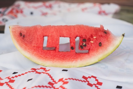 a fresh piece of watermelon and a tablecloth with a pattern on a wooden tableの写真素材