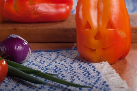 Sweet peppers on wooden table, pumpkin face for Halloween, gala dinnerの写真素材