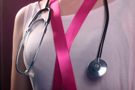 pink ribbon and a stethoscope on his chest, healthcare, medicine and breast cancer conceptの写真素材