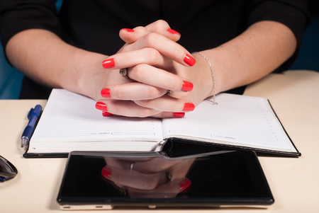 Woman with folded hands sits at a Desk, a tablet and a notebook lie on the desktop, the concept of business womenの写真素材