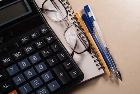 Calculator, glasses and a Notepad on the table, leather notebook, Business conceptの写真素材