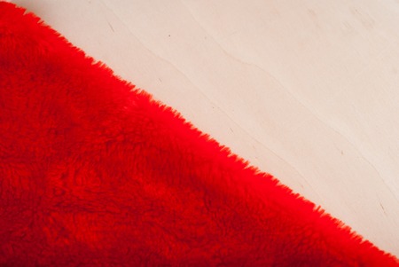Red fur on a wooden table, a Red Santa hat on wooden background, holiday Christmasの写真素材