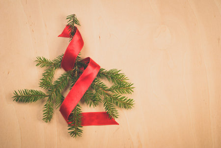 Pine branch on wooden background, a Small Christmas tree with red ribbon, Happy Christmasの写真素材
