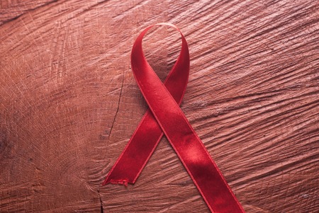 red ribbon on the wooden background AIDSの写真素材