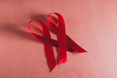red ribbon on the wooden background AIDSの写真素材