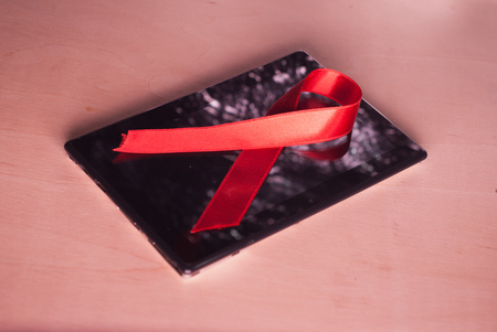 PC tablet, red ribbon AIDS, wooden background,の写真素材