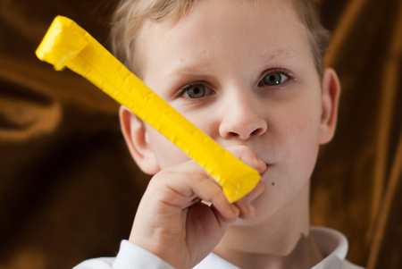 A little boy with a yellow squeaky toy, a cute playful child in a white shirtの写真素材
