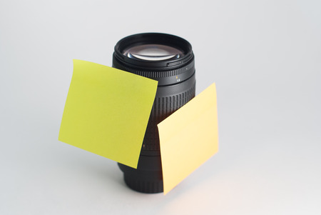 Black camera lens, is attached with a sticker for reminders, light backgroundの写真素材