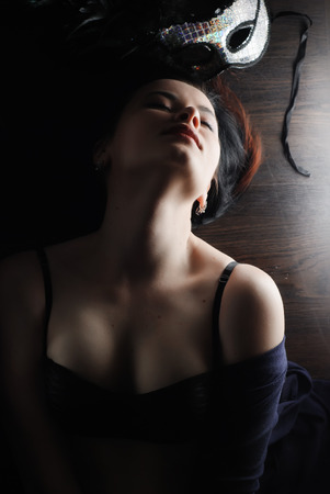 sexy woman with mask, lying on a wooden floor, a gentle and sensual girl with beautiful bodyの写真素材