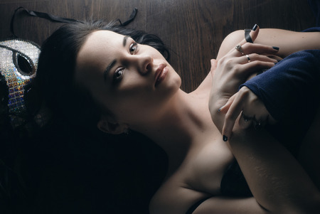 sexy woman with mask, lying on a wooden floor, a gentle and sensual girl with beautiful bodyの写真素材