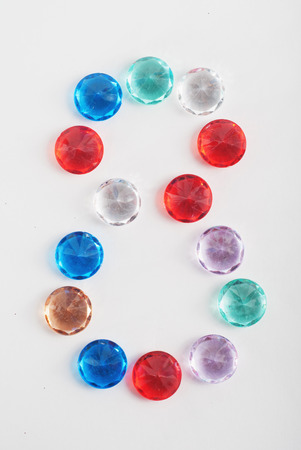 Multicolored faceted stones in the shape of the number 8 on a white background, international women's day, the figure 8の写真素材