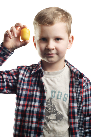 A little boy holds a toy in his hand with a smile, isolated white background, guy in a plaid shirtの写真素材
