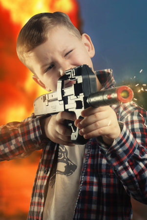 Little boy in shirt with a black gun, boy posing, the man takes aim ,の写真素材